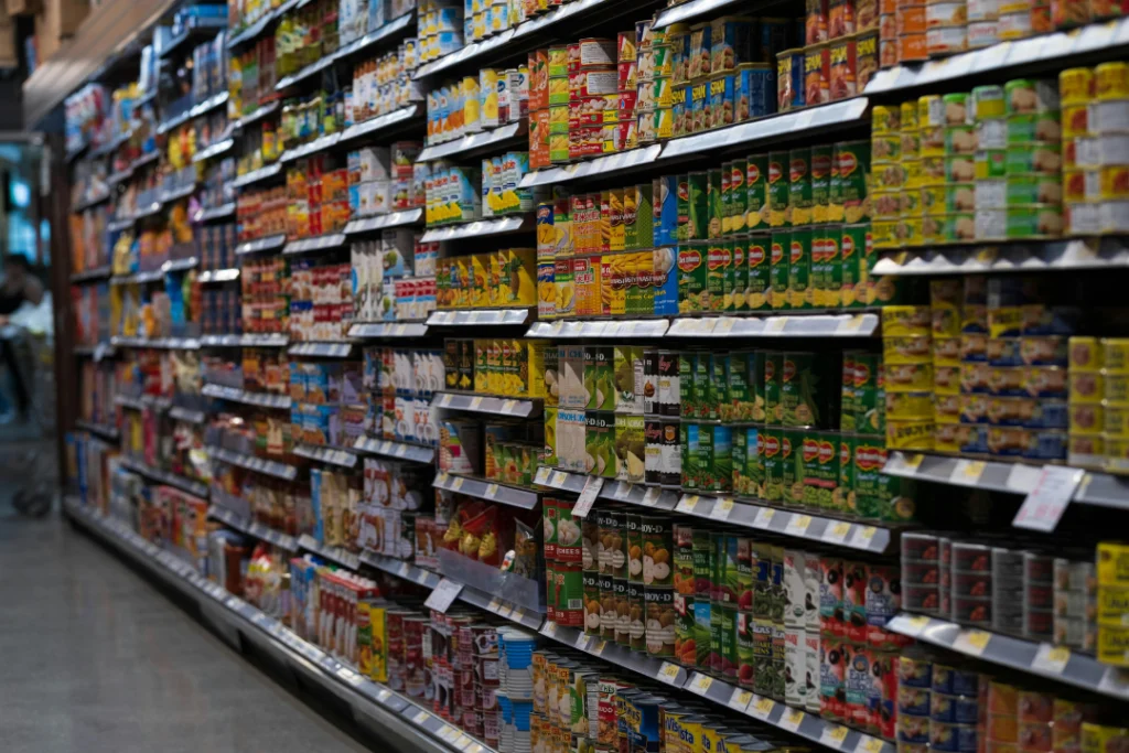 Consumidor analisa preços em supermercado: alimentos lideram a alta da inflação em abril de 2026 | Foto: Reprodução/ Pixels